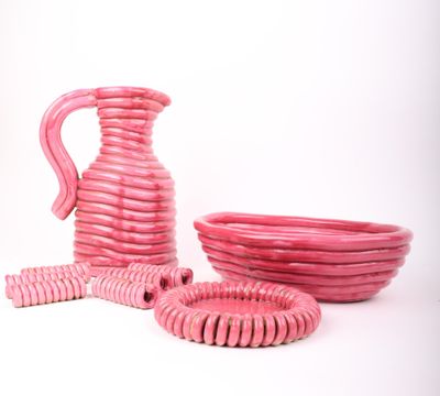 un vase, un bol et une assiette roses sur fond blanc