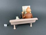 a figurine of a man sitting on a bench with a cat