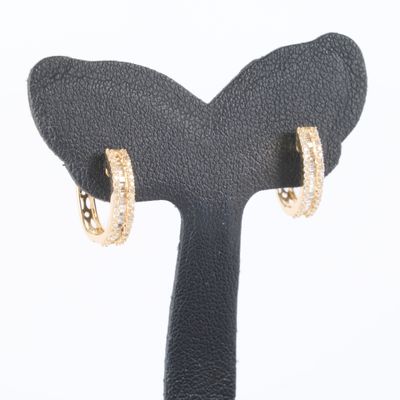 un gros plan sur une paire de boucles d'oreilles créoles en or posées sur un présentoir noir