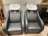 une paire de fauteuils en cuir gris, avec un lavabo et un miroir au mur