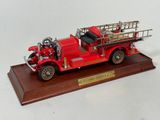 a model of a red fire truck on a wooden base