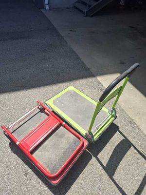 a red and green hand truck sitting on the ground