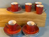 quatre tasses et soucoupes rouges posées sur un support en bois