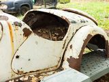 a rusted out old car sitting on the ground