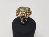 a gold ring with a green stone on top of a black box