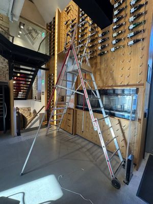 une échelle posée devant un mur de bouteilles de vin
