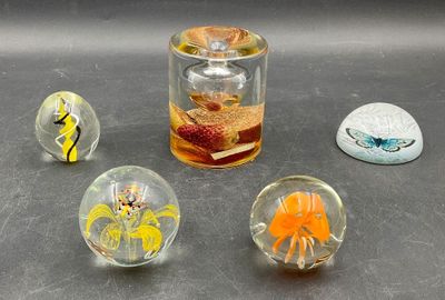 four glass marbles sitting on a table next to a glass jar
