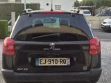 une petite voiture noire garée devant une maison blanche