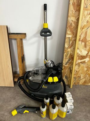 a black and yellow steam cleaner and some cleaning supplies on the floor