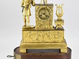 une horloge en or posée sur un socle en bois orné d'une statue représentant un homme