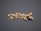 a gold broochle with leaves and flowers on a black background