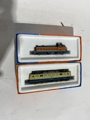 deux trains miniatures posés dans une boîte sur une table
