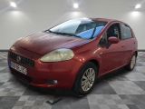 La petite voiture rouge est garée dans le garage, sur le sol à damier.