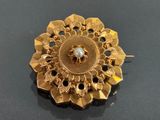 a gold brooch with a white stone in the center