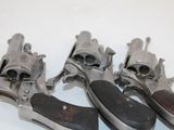 three old revolvers sitting on top of each other on a white surface