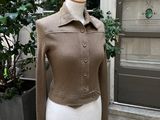 veste en tricot marron sur un mannequin, avec une plante en pot en arrière-plan