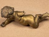 a small bronze statue of a boy laying on the ground