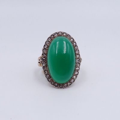 gros plan d'une bague avec une pierre verte entourée de diamants