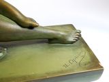a bronze statue of a woman laying down on a book