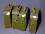 quatre boîtes métalliques de couleur vert militaire, munies d'étiquettes, posées sur une table