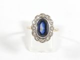 gros plan d'une bague avec une pierre bleue entourée de diamants