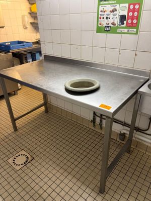 une grande table en métal sur laquelle est posé un saladier, dans une cuisine