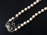 a close up of a necklace with pearls on a black surface