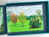 two paintings of trees in a blue box on a table