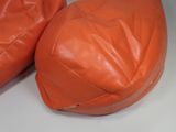 pair of orange leather bean bags sitting on top of a white table