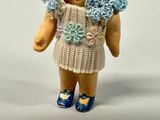 a small doll that is wearing a dress and blue shoes