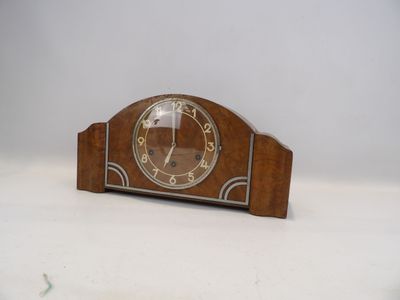 une petite horloge en bois posée sur une table, sur fond blanc