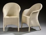 pair of white wicker chairs against a black background