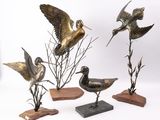 trois statues d'oiseaux en bronze posées sur des socles en bois, sur un fond blanc