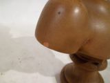une sculpture en bois représentant une tête d'homme posée sur une table