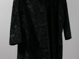 a black coat hanging on a hanger against a white wall