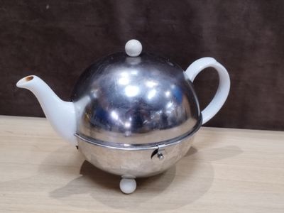 a silver teapot on a wooden table with a brown background