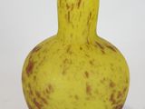 a yellow and brown vase sitting on a white surface