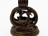 une figurine antique en bronze représentant un dragon, posée sur un socle