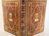 un vieux livre à la couverture dorée posé sur une table blanche