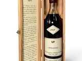 une vieille bouteille de vin dans un coffret en bois, accompagnée d'une lettre manuscrite