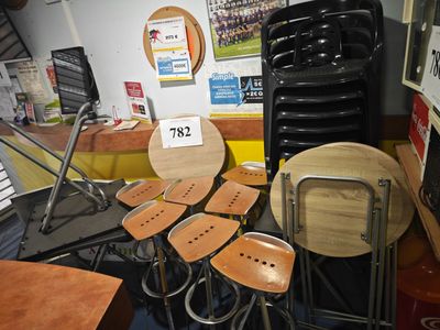 de nombreuses chaises et tabourets dans une pièce où est accrochée une affiche au mur