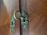 a close up of a door handle on a wooden cabinet