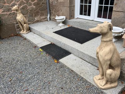 une statue représentant un chien assis sur les marches à l'extérieur d'une maison