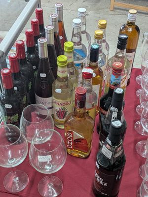 many bottles and glasses on a table with a red table cloth