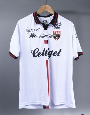 the soccer shirt is hanging on a hanger on a wall