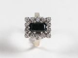 un gros plan d'une bague en diamant noir et blanc posée sur une surface blanche