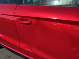 a red car parked in a parking lot with its door open
