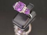 un gros plan d'une bague sertie d'une pierre violette et de diamants