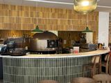 des tables et des chaises dans un restaurant doté d'un comptoir, avec un four à pizza à l'arrière