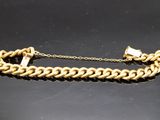 gros plan d'un bracelet en chaîne en or sur une surface noire